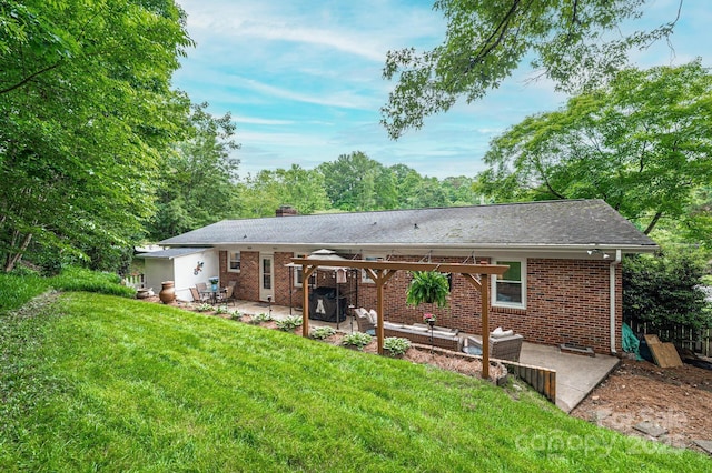 rear view of house with a patio area, a pergola, brick siding, and a yard