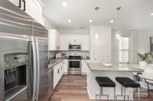 3004 Marlowe Ave, Charlotte, NC 28208 - kitchen featuring stainless steel appliances, a breakfast bar area, light stone countertops, white cabinets, and dark wood finished floors