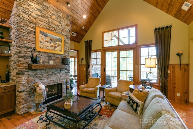 living area featuring high vaulted ceiling, wood finished floors, a fireplace, wooden ceiling, and plenty of natural light