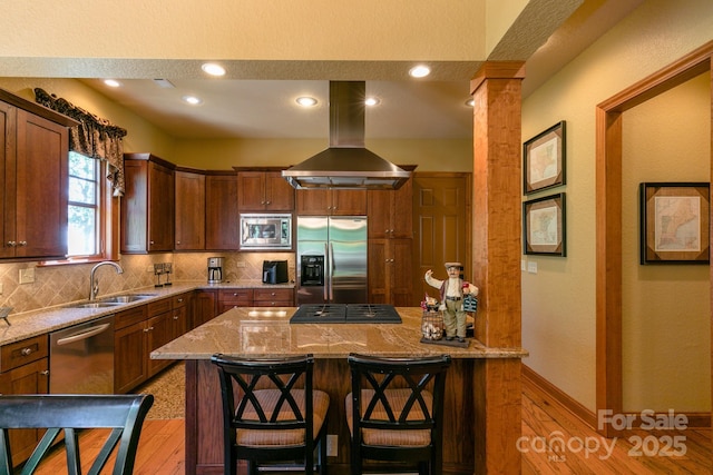 kitchen featuring stainless steel appliances, island exhaust hood, a sink, decorative backsplash, and recessed lighting