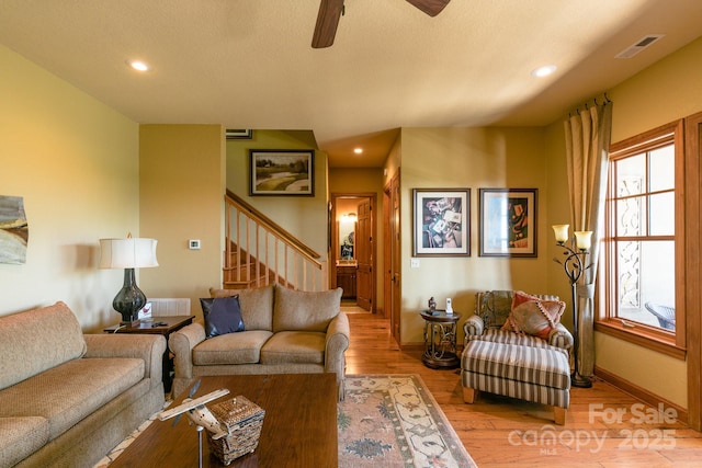 living area featuring stairway, light wood-style flooring, ceiling fan, baseboards, and recessed lighting