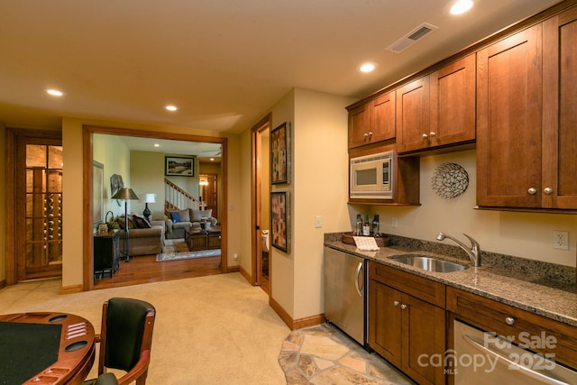 kitchen with a sink, appliances with stainless steel finishes, stone counters, light carpet, and recessed lighting