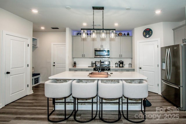 11951 Old Statesville Rd, Huntersville, NC 28078 - kitchen featuring appliances with stainless steel finishes, a breakfast bar area, light countertops, gray cabinets, and dark wood finished floors