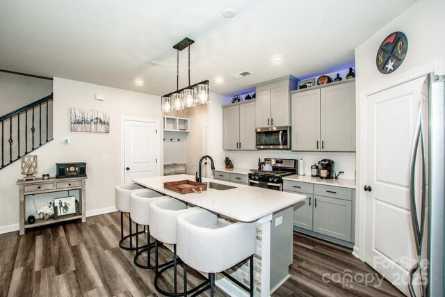 11951 Old Statesville Rd, Huntersville, NC 28078 - kitchen with stainless steel appliances, gray cabinets, a sink, a kitchen bar, and dark wood-type flooring