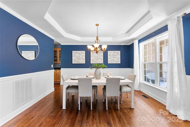 6300 Latta Springs Cir, Huntersville, NC 28078 - dining space with a tray ceiling, a chandelier, dark wood-type flooring, a wainscoted wall, and ornamental molding