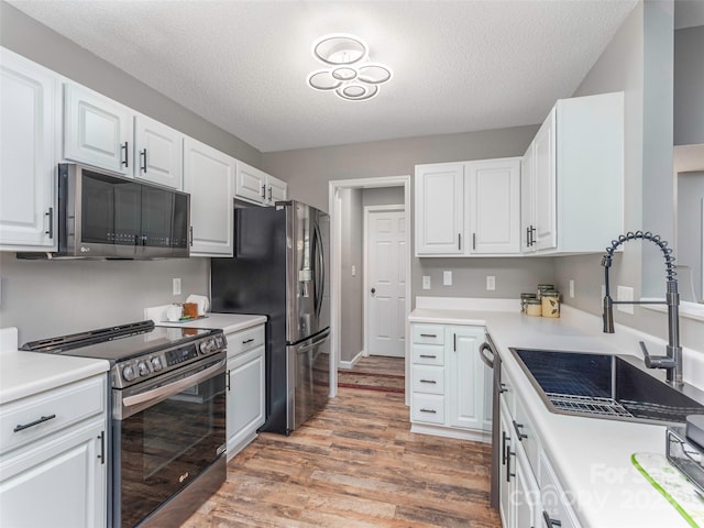 379 Running Briar Rd, Fletcher, NC 28732 - kitchen featuring stainless steel appliances, a sink, light wood-style flooring, white cabinets, and a textured ceiling