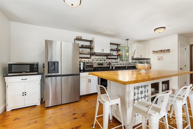 7015 Lavern St, Charlotte, NC 28215 - kitchen featuring appliances with stainless steel finishes, butcher block countertops, open shelves, a breakfast bar, and tasteful backsplash