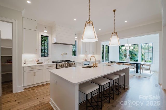 1625 Club Rd, Charlotte, NC 28205 - kitchen with high end stove, light wood-type flooring, a breakfast bar, tasteful backsplash, and white cabinetry