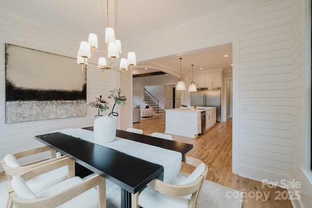 1625 Club Rd, Charlotte, NC 28205 - dining area with light wood-style flooring, arched walkways, stairs, wood walls, and a chandelier