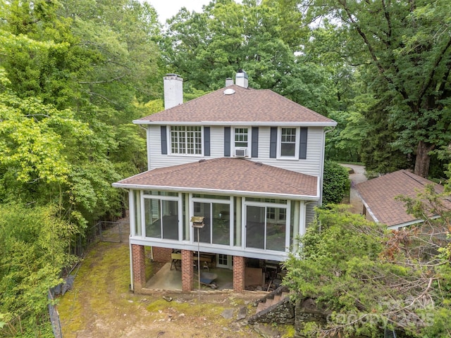 93 Villa Barbara Ln, Tryon, NC 28782 - view of front of house with a sunroom, roof with shingles, a chimney, and a view of trees
