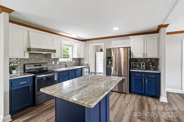 2021 Beamguard Rd, Clover, SC 29710 - kitchen with appliances with stainless steel finishes, blue cabinetry, wall chimney exhaust hood, a sink, and crown molding