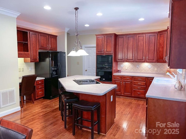 15494 Donnington Dr, Charlotte, NC 28277 - kitchen with black appliances, a sink, ornamental molding, a center island, and light countertops