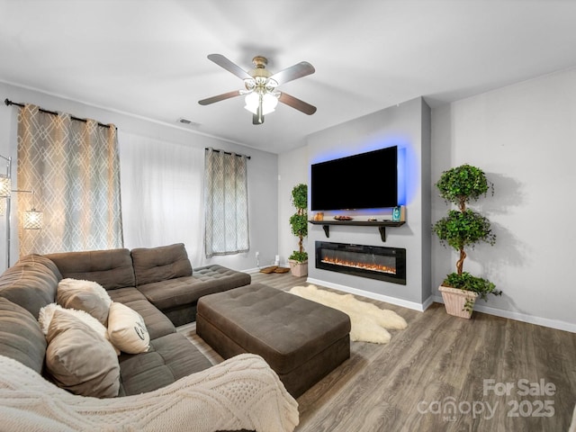 10426 Kempsford Dr, Charlotte, NC 28262 - living area with a glass covered fireplace, wood finished floors, a ceiling fan, and baseboards