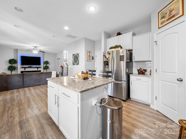 10426 Kempsford Dr, Charlotte, NC 28262 - kitchen with stainless steel fridge with ice dispenser, light wood-style flooring, a kitchen island, a ceiling fan, and tasteful backsplash
