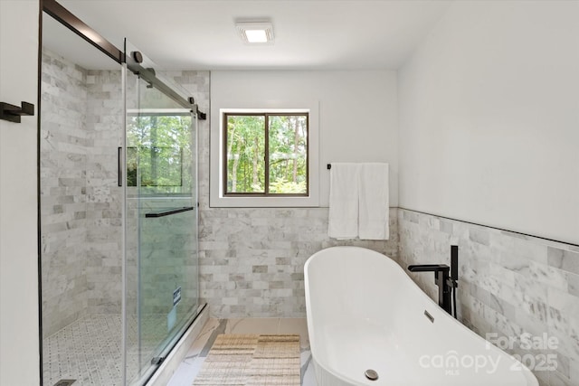 5033 Waxhaw Indian Trail Rd, Matthews, NC 28104 - bathroom featuring tile walls, a stall shower, a freestanding bath, and tile patterned floors