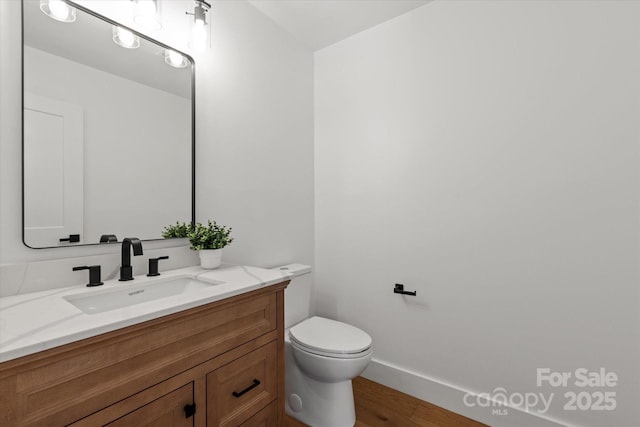5033 Waxhaw Indian Trail Rd, Matthews, NC 28104 - half bathroom featuring toilet, vanity, wood finished floors, and baseboards