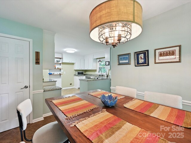 2911 Butter Churn Ln, Matthews, NC 28105 - tiled dining space featuring a sink, a chandelier, and baseboards