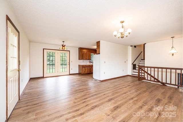 3020 Doc Pugh Rd, Connelly Springs, NC 28612 - unfurnished living room featuring light wood-type flooring, a chandelier, a textured ceiling, baseboards, and stairs