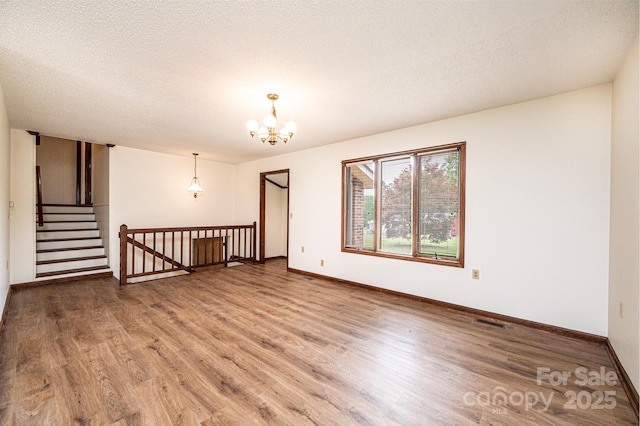 3020 Doc Pugh Rd, Connelly Springs, NC 28612 - empty room with wood finished floors, baseboards, a chandelier, and a textured ceiling