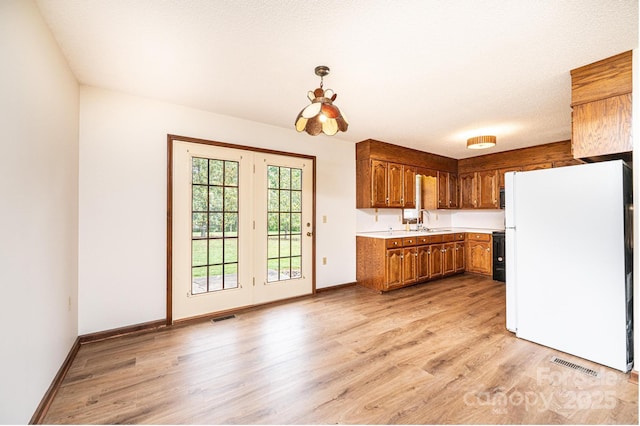 3020 Doc Pugh Rd, Connelly Springs, NC 28612 - kitchen with freestanding refrigerator, a sink, light countertops, brown cabinetry, and light wood-style floors