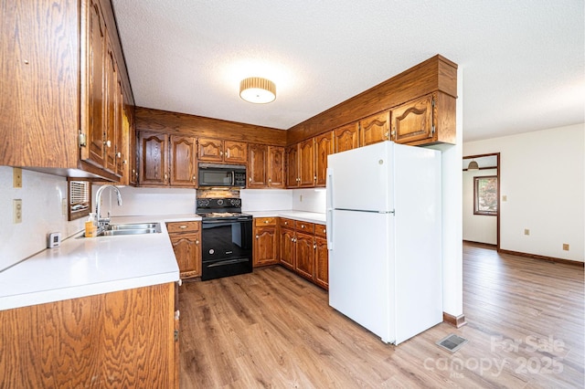 3020 Doc Pugh Rd, Connelly Springs, NC 28612 - kitchen featuring black appliances, a sink, light wood-style floors, brown cabinetry, and light countertops
