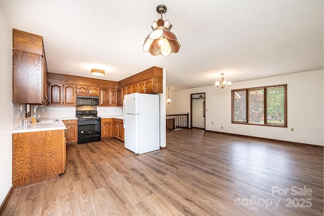3020 Doc Pugh Rd, Connelly Springs, NC 28612 - kitchen featuring black appliances, brown cabinets, wood finished floors, a chandelier, and light countertops
