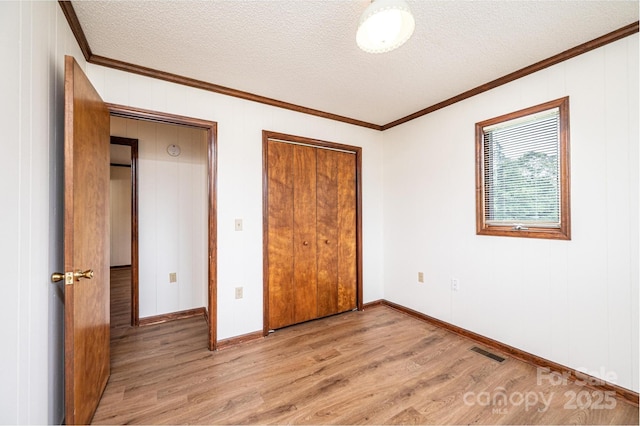 3020 Doc Pugh Rd, Connelly Springs, NC 28612 - unfurnished bedroom with light wood-style flooring, crown molding, a textured ceiling, a closet, and baseboards