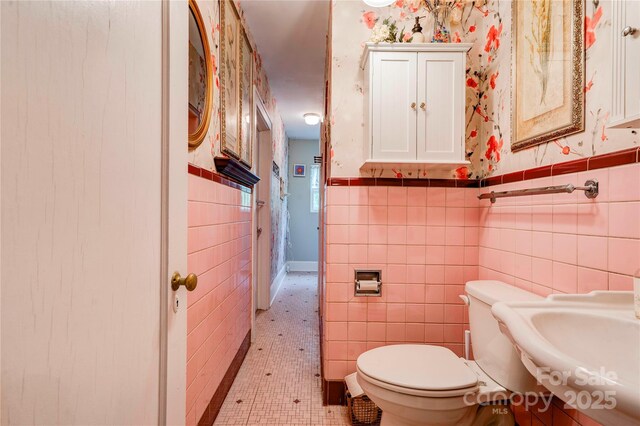 611 E Marion St, Shelby, NC 28150 - bathroom featuring tile walls, toilet, wainscoting, a sink, and wallpapered walls