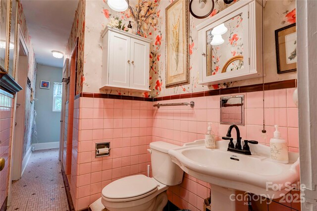 611 E Marion St, Shelby, NC 28150 - bathroom with toilet, wallpapered walls, wainscoting, a sink, and tile walls