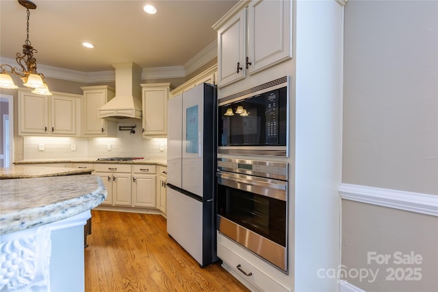 1009 Brookline Dr, Huntersville, NC 28078 - kitchen featuring stainless steel appliances, custom exhaust hood, decorative light fixtures, tasteful backsplash, and light wood-style floors