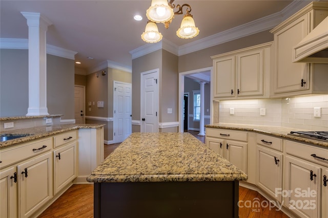1009 Brookline Dr, Huntersville, NC 28078 - kitchen featuring ornate columns, cream cabinetry, custom exhaust hood, wood finished floors, and light stone counters