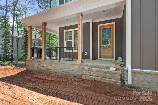 6782 Kingfisher Ct, Denver, NC 28037 - doorway to property featuring board and batten siding, covered porch, and stone siding