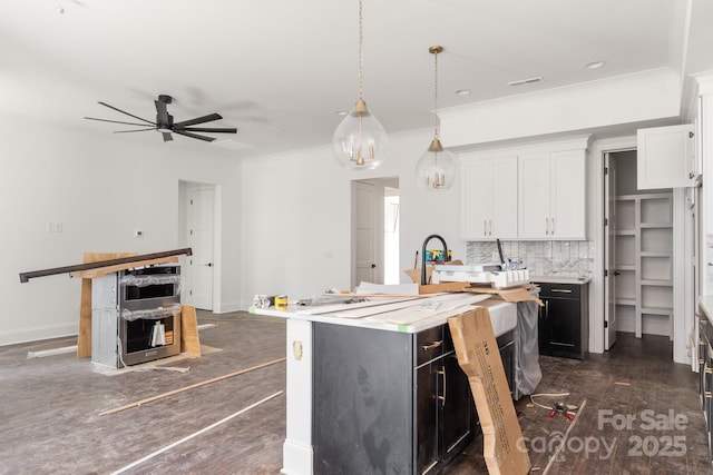 6782 Kingfisher Ct, Denver, NC 28037 - kitchen with white cabinets, an island with sink, tasteful backsplash, light countertops, and decorative light fixtures