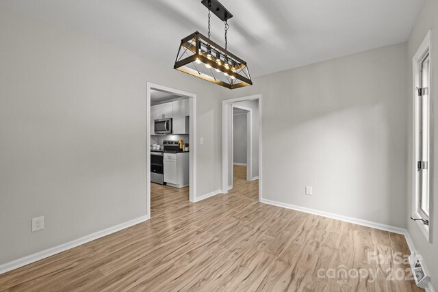 13446 Idlefield Ln, Matthews, NC 28105 - unfurnished dining area featuring light wood-type flooring and baseboards