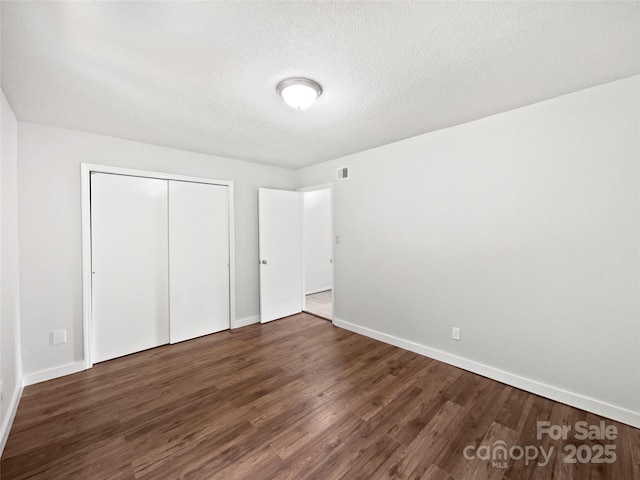 1908 Harvest Ln Unit 5, Charlotte, NC 28210 - unfurnished bedroom featuring dark wood-style floors, baseboards, a closet, and a textured ceiling