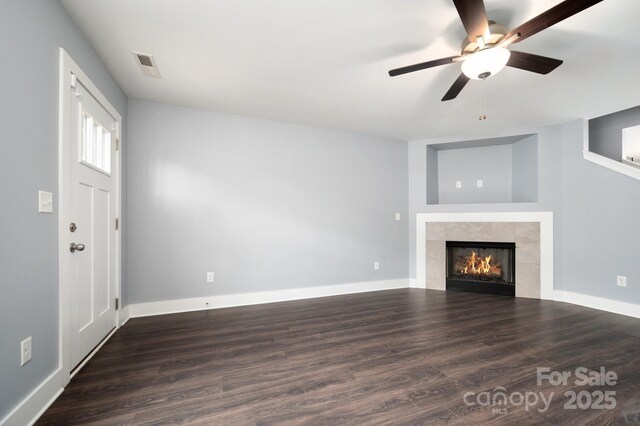 207 Stoney Point Way, Candler, NC 28715 - unfurnished living room with a tiled fireplace, wood finished floors, a ceiling fan, and baseboards