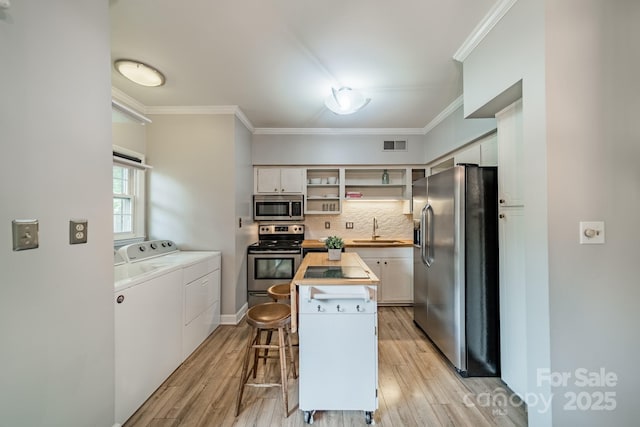 5927 Quail Hollow Rd Unit H, Charlotte, NC 28210 - kitchen with stainless steel appliances, washer and dryer, a sink, a center island, and ornamental molding