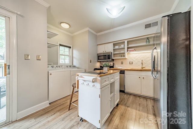 5927 Quail Hollow Rd Unit H, Charlotte, NC 28210 - kitchen featuring stainless steel appliances, washer and clothes dryer, light wood-style flooring, crown molding, and a sink