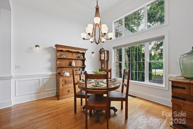 12900 Westmoreland Rd, Huntersville, NC 28078 - dining area featuring a chandelier, light wood finished floors, crown molding, a towering ceiling, and a wainscoted wall