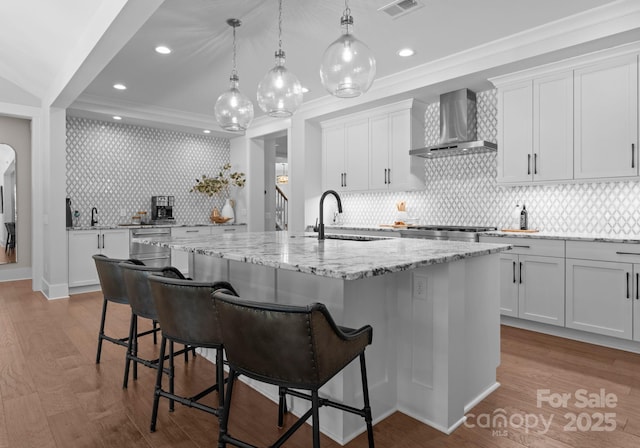 4021 Redwood Ave, Charlotte, NC 28205 - kitchen featuring wall chimney range hood, a sink, a kitchen island with sink, a breakfast bar area, and tasteful backsplash