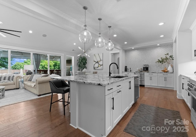 4021 Redwood Ave, Charlotte, NC 28205 - kitchen with a sink, ornamental molding, a center island with sink, white cabinetry, and a kitchen breakfast bar