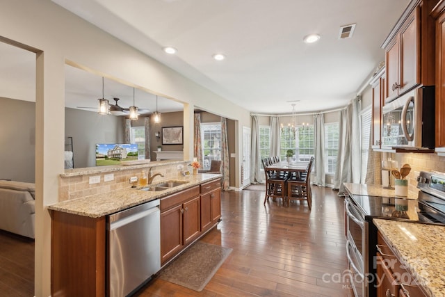 4430 Bravery Pl SW, Concord, NC 28027 - kitchen featuring appliances with stainless steel finishes, a sink, brown cabinetry, backsplash, and decorative light fixtures