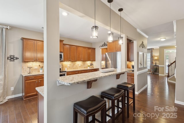 4430 Bravery Pl SW, Concord, NC 28027 - kitchen with appliances with stainless steel finishes, brown cabinets, dark wood-type flooring, and a kitchen breakfast bar