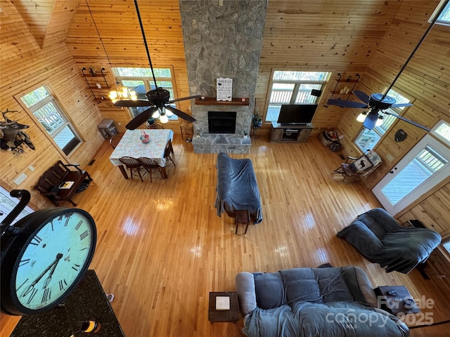 658 Green Point Ln, Boomer, NC 28606 - living room with a ceiling fan, a high ceiling, wood walls, a stone fireplace, and wood finished floors