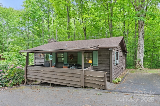 37 Sassafras Ln, Maggie Valley, NC 28751 - view of front facade featuring a chimney, a shingled roof, and a view of trees