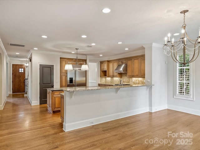 1522 High St, Charlotte, NC 28211 - kitchen featuring stainless steel built in fridge, under cabinet range hood, a peninsula, a chandelier, and crown molding