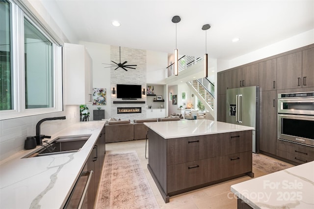 5925 Creola Rd, Charlotte, NC 28270 - kitchen featuring stainless steel appliances, a sink, modern cabinets, a fireplace, and dark brown cabinetry