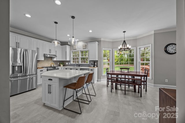 16028 Cranleigh Dr, Huntersville, NC 28078 - kitchen with stainless steel appliances, under cabinet range hood, white cabinetry, backsplash, and light countertops