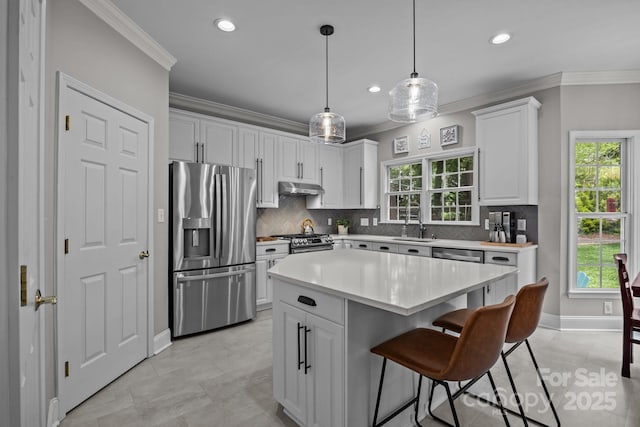 16028 Cranleigh Dr, Huntersville, NC 28078 - kitchen with appliances with stainless steel finishes, under cabinet range hood, crown molding, light countertops, and a sink