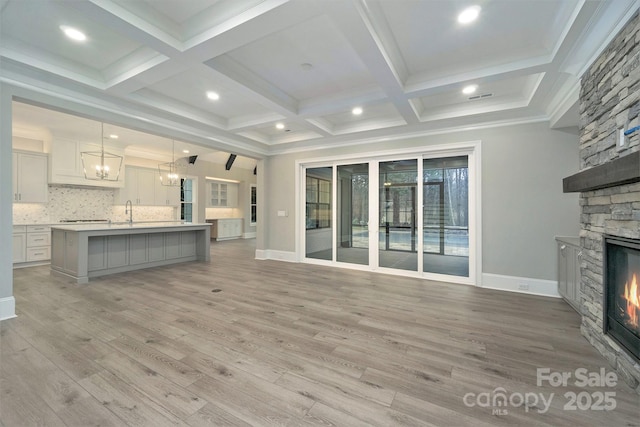 7215 Alexander Rd Unit 4, Charlotte, NC 28270 - unfurnished living room with a stone fireplace, a chandelier, baseboards, light wood-type flooring, and beamed ceiling